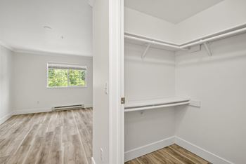 A room with white walls and wooden flooring with a window.